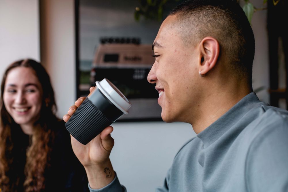 Man in cafe holding the Circular Returnable Cup up to his mouth.